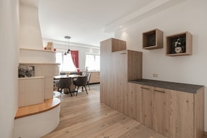 A modern kitchen with wooden cabinets, a dining area with chairs, and a built-in bench.