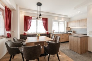 Una cocina moderna con armarios de madera, una isla central y un comedor con sillas.
