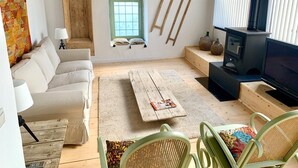 Un salon avec un canapé, une table basse, un téléviseur, une cheminée et une fenêtre.