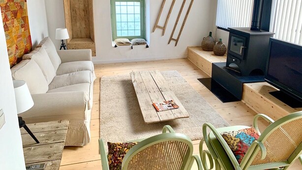 Een gezellige woonkamer met een bank, een salontafel, een televisie en een open haard.