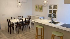 Een moderne keuken met een marmeren aanrecht, houten stoelen en twee barstoelen.