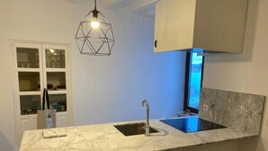 Een keuken met een marmeren aanrecht, twee krukken, een hanglamp en een raam met uitzicht.