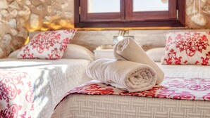 A neatly made bed with rolled towels, patterned pillows, and a stone wall. - Casa del Sol with Sea View, Wi-Fi, Pool, Balcony & Terrace; Street Parking (Búger)