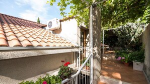 A residential area with a tiled roof, a white wall, and a balcony with potted plants. - Apartment Srđ  (Dubrovnik)
