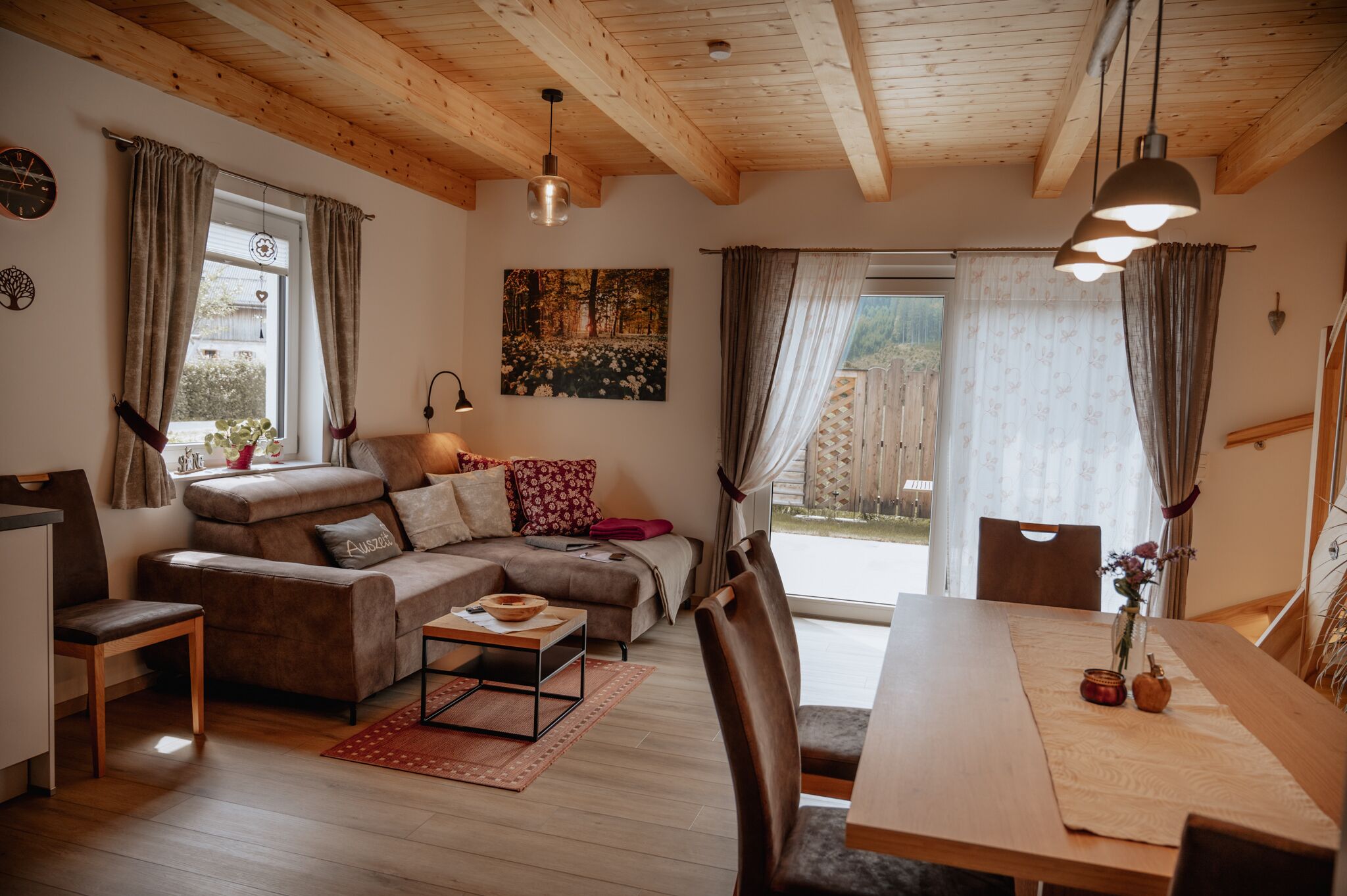 A cozy living room with a sofa, a dining table, and a wooden ceiling.