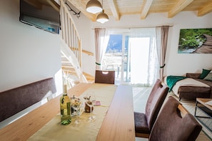Ein gemütliches Wohnzimmer mit Holztisch, einer Couch und einer Treppe, die zu einem Balkon führt.