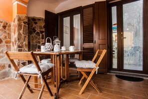 A wooden table with chairs, a stone wall, and a door with a frosted glass panel.