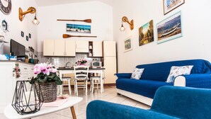 A compact living space with a kitchenette, a blue sofa, and a dining area. - Holiday Apartment ‘Casa Vacanze Pula' with Balcony & Terrace (Pula)