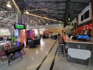 A modern restaurant with a high ceiling, exposed beams, and a bar area. - Carliza Hotel Apapa (Lagos)