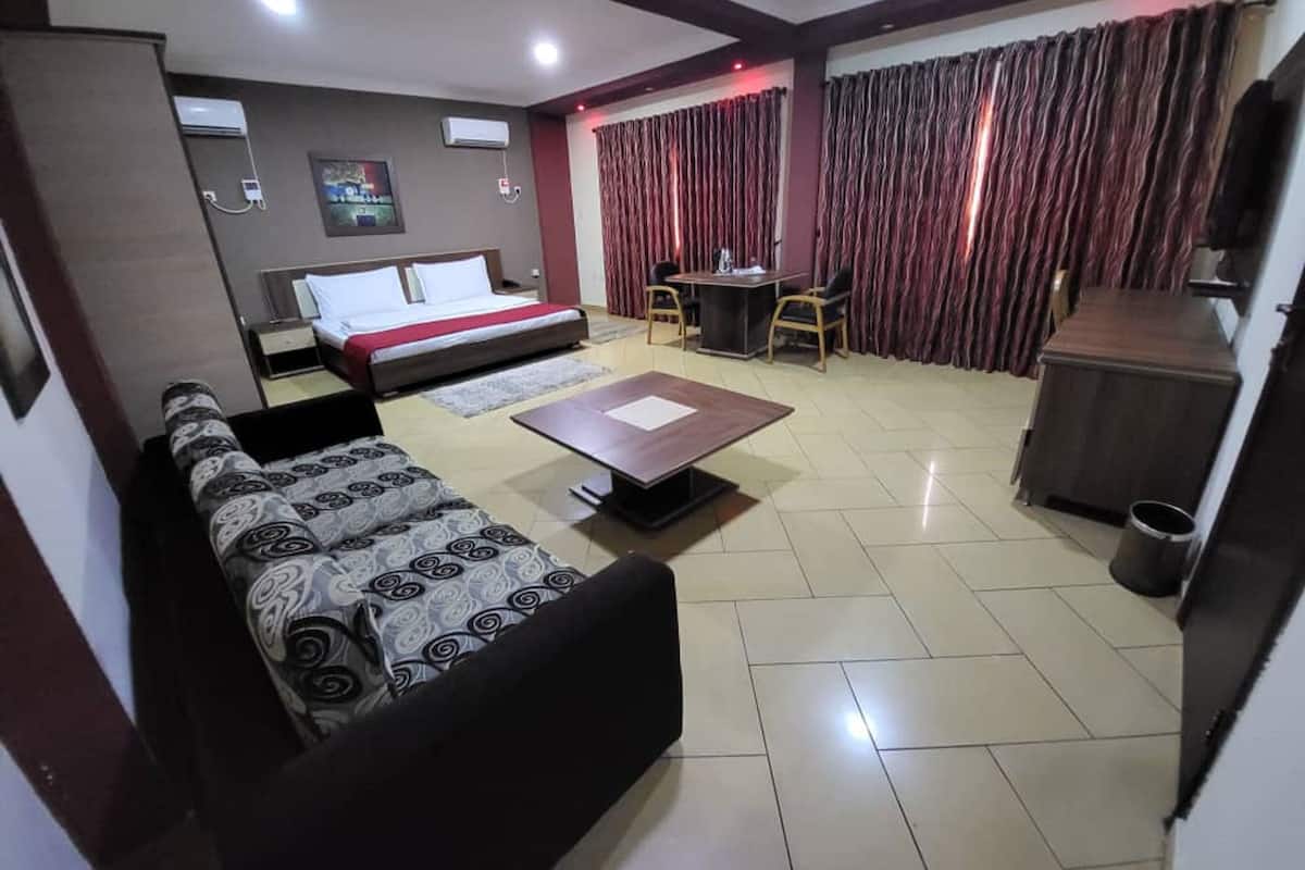 A hotel room with a bed, a sofa, a desk, and a small table.