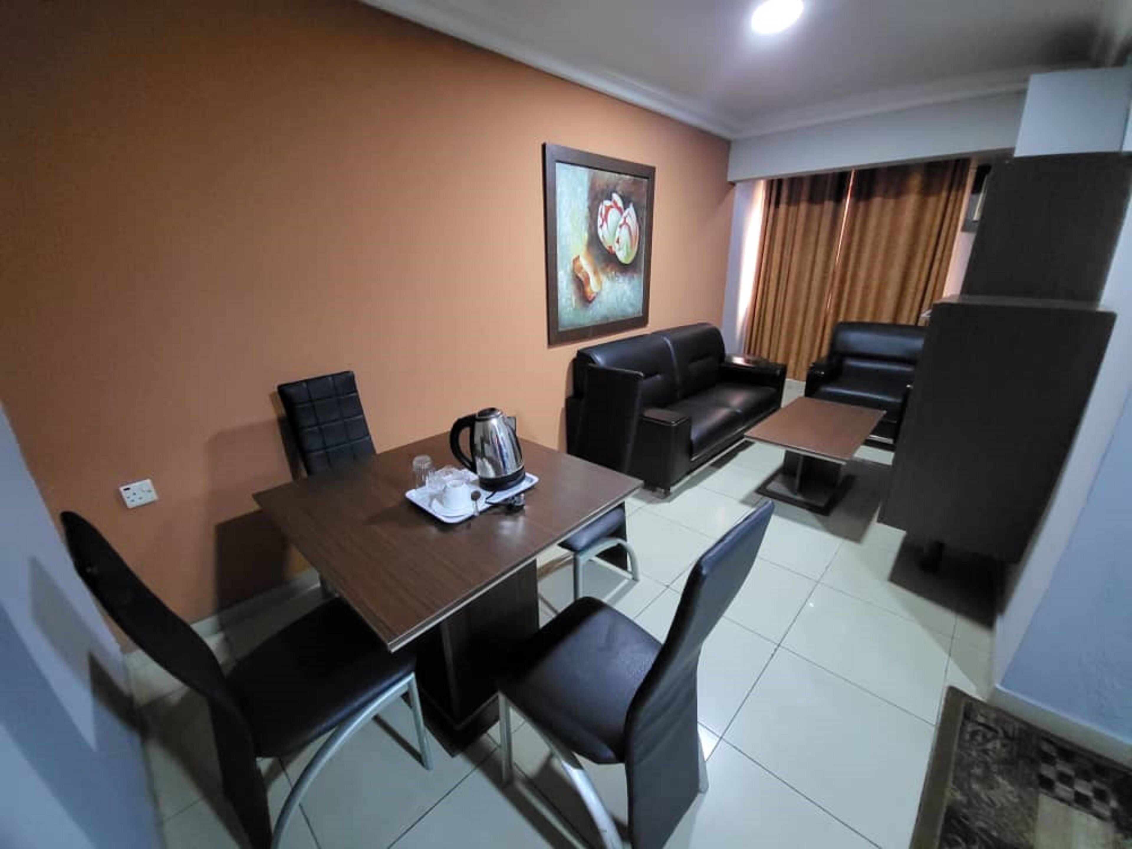 A compact living room with a dining table, black leather sofa, and a coffee table.