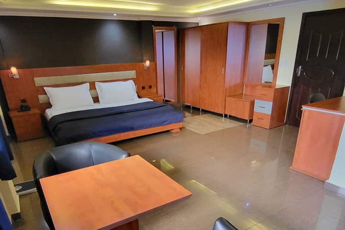 A modern hotel room with a bed, a desk, and a seating area.