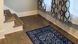 Un escalier avec des marches en bois et une rampe, un tapis à motifs sur le sol et une fenêtre avec des rideaux à motifs.
