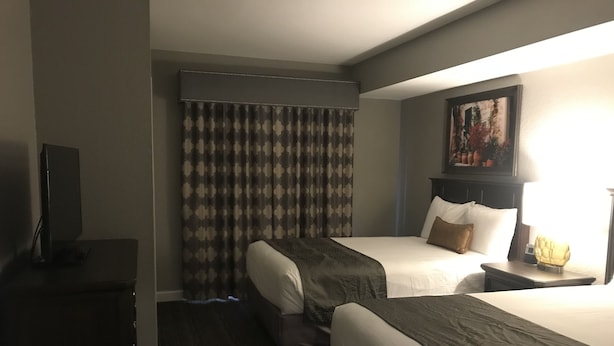 A hotel room with two beds, a flat-screen TV, a painting on the wall, and a bedside table with a lamp. - Wyndham Great Smokies Lodge at Wilderness water park(s) included (Sevierville)
