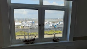 A room with a large window overlooking a marina with boats. - Marina View, Lovely Upper 3 Bedroom Apartment (Troon)