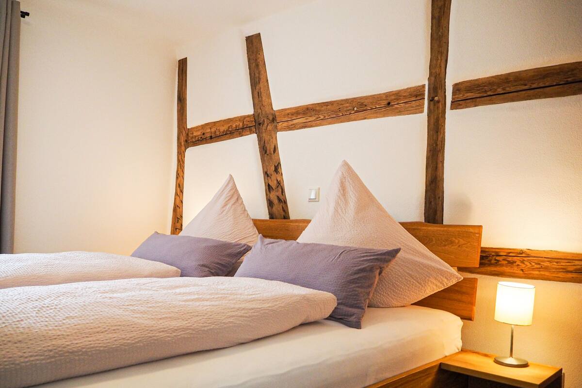A bed with a wooden headboard, two pillows, and a bedside lamp.