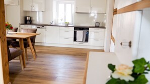 Eine moderne Küche mit weißen Schränken, einem Holztisch und einer Kaffeemaschine.