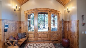 Un interior de madera con un amplio arco de entrada, un banco con cojines y una alfombra con estampado de piedra.