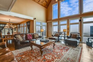 A spacious living room with leather sofas, a glass coffee table, and a large rug.