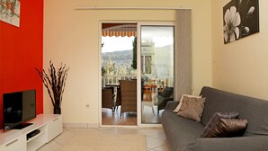 A living room with a TV, sofa, and a sliding glass door leading to a balcony. - HOUSE  DRAGOJEVIC (Vela Luka)
