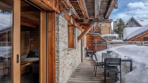 A wooden deck with stone walls, a bench, and a table covered in snow.