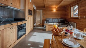 A wooden cabin with a kitchen, dining area, and a cozy living space.