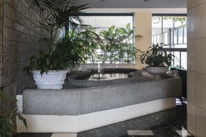 A modern indoor garden with potted plants and a water feature.