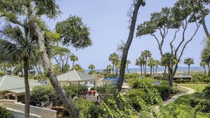 A resort with a pool area, palm trees, and a view of the ocean. - 5105 Hampton Place - Amazing Views (Hilton Head Island)