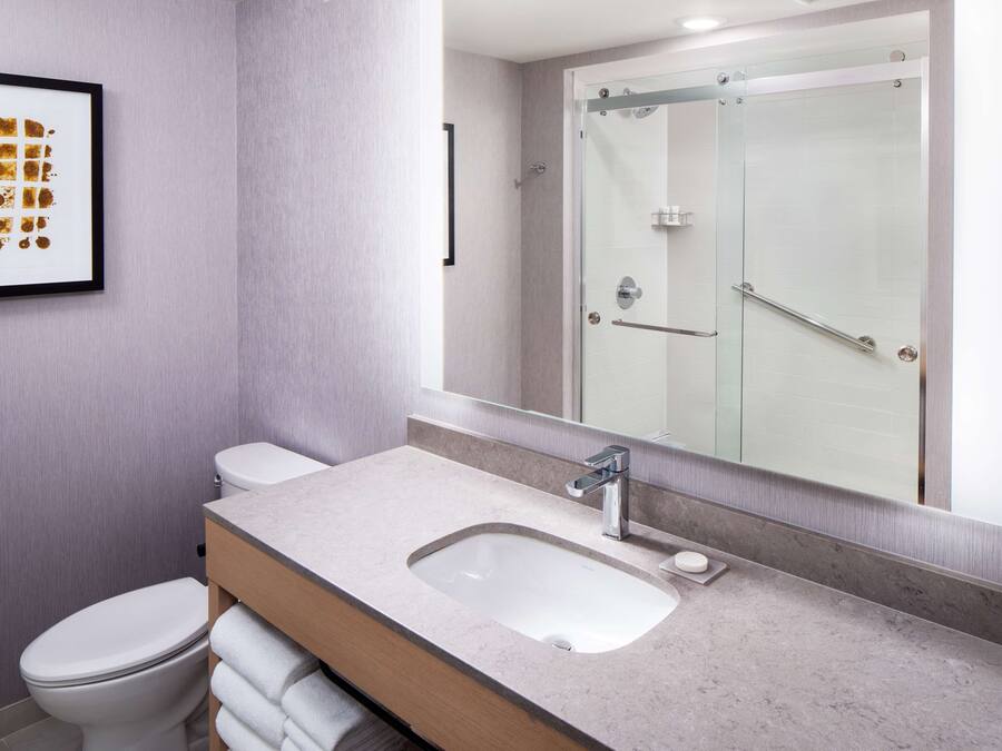 A modern bathroom with a sink, mirror, and glass shower enclosure.