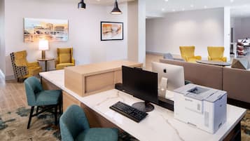 Een moderne hotellobby met een receptiebalie, een zithoek, kunstwerken en een grote spiegel.