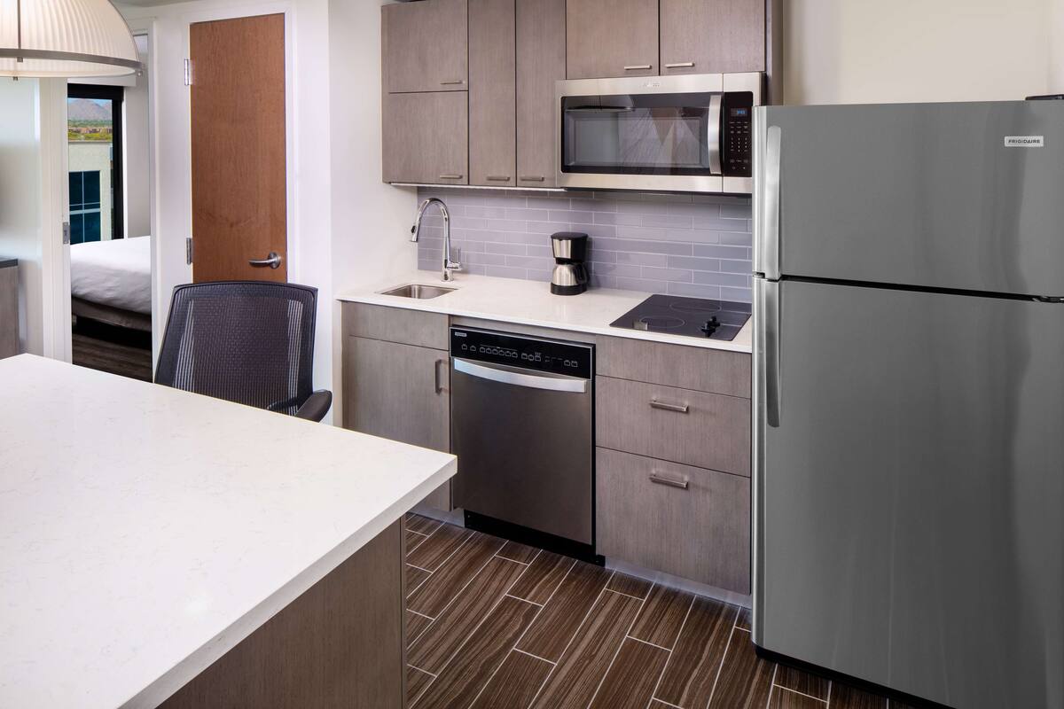 Una cocina de hotel compacta con lavavajillas, microondas y refrigerador.