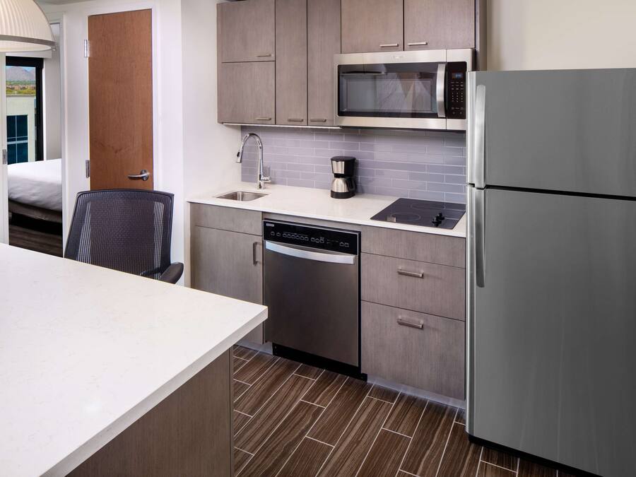 Uma cozinha de hotel compacta, com lava-louças, micro-ondas e frigorífico.
