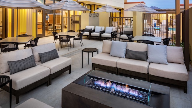 A modern outdoor lounge area with sofas, chairs, and a glass-top coffee table with a fire feature. - Hyatt House North Scottsdale (Scottsdale)