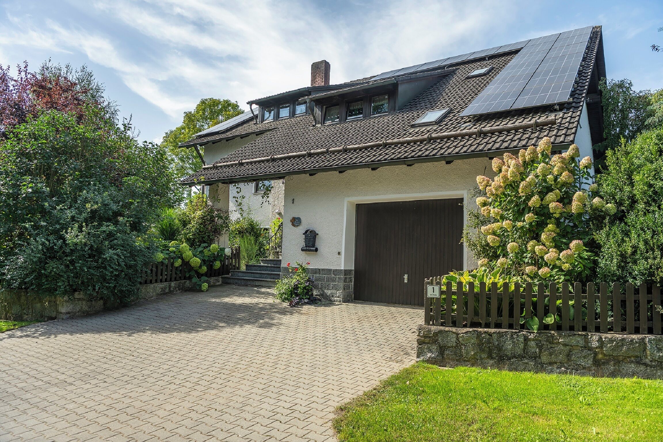 A house with a tiled roof, a garage, and a paved driveway.