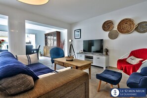 Un soggiorno moderno con un divano, poltrone, televisore e decorazioni a parete.