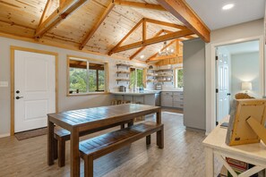 A spacious kitchen with wooden beams, a large wooden table, and built-in shelves. - Modern Cabin on Private Lake: Gateway to the Sequoias (Springville)