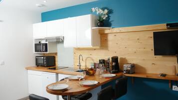 A compact kitchen with white cabinets, a wooden countertop, a microwave, a toaster, and a sink.