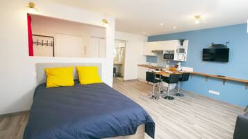 Un dormitorio moderno con una cama grande, un escritorio y una kitchenette.
