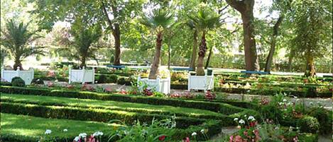 Un jardín bien cuidado con setos ordenados y diversas plantas florecientes.