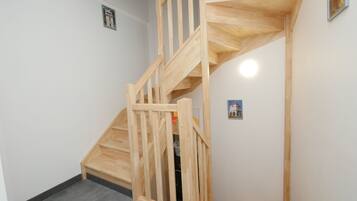 A wooden staircase with a simple design, leading to a room with a white wall and a small picture frame.
