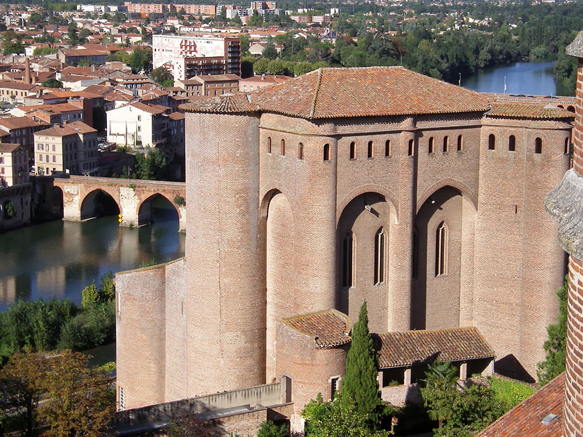 A large, historic building with a prominent arched entrance and a river in the background.