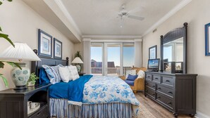 A bedroom with a large bed, a dresser, a nightstand, and a window with a view. - Gorgeous 3 BR condo on the famous OC Boardwalk, offers luxury and location! (Ocean City)