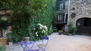 Un patio con muro de piedra, plantas en macetas y un sendero de grava.