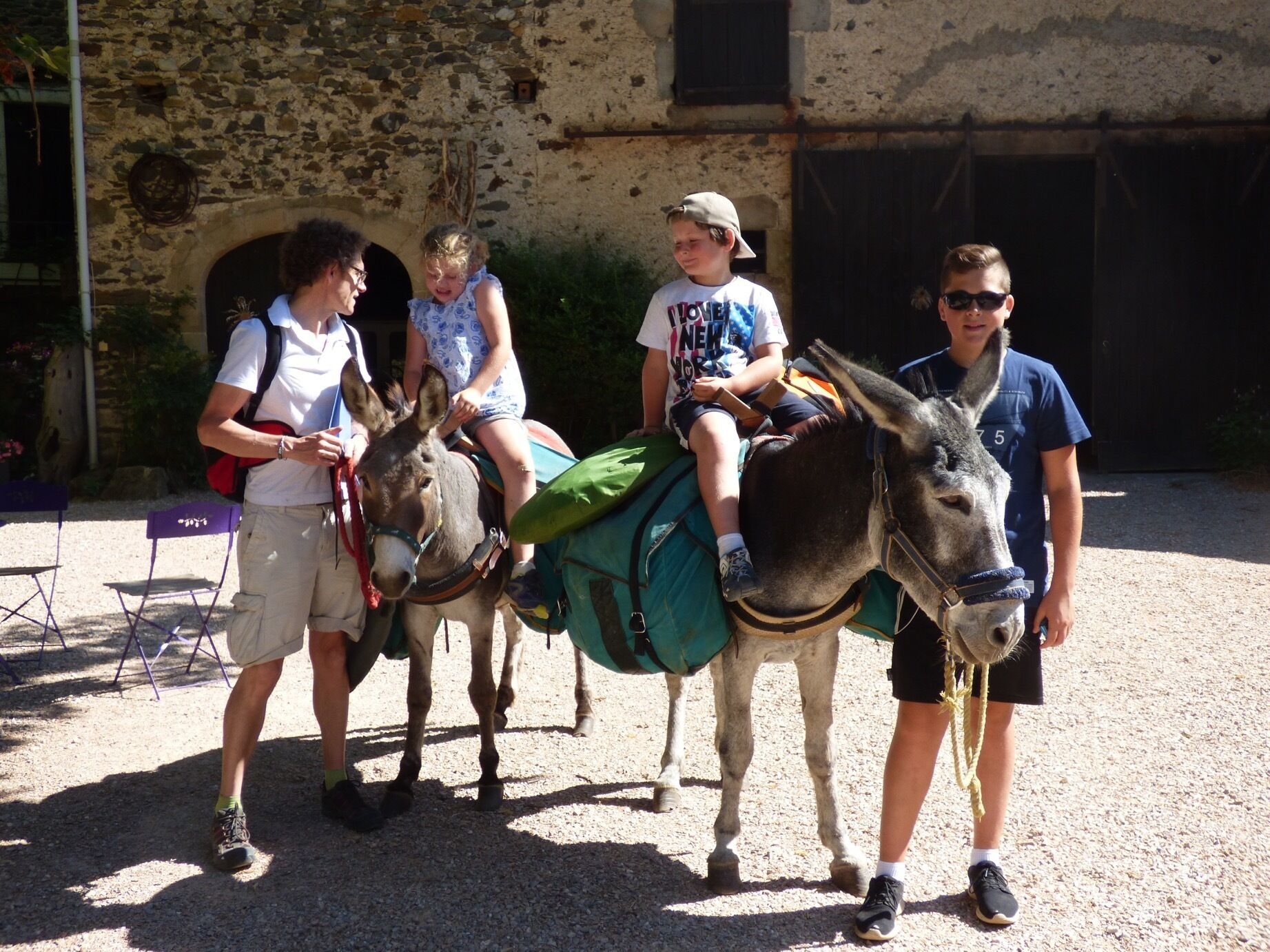Un groupe de personnes accompagnées d’ânes, dont l’un est mené par une personne portant une chemise bleue.