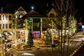 A street view at night with buildings adorned with holiday lights, a visible restaurant, and a clear sidewalk.