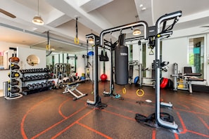 Une salle de sport équipée de divers appareils d’exercice, dotée d’un mur avec des miroirs et d’un sac de frappe fixé au mur.