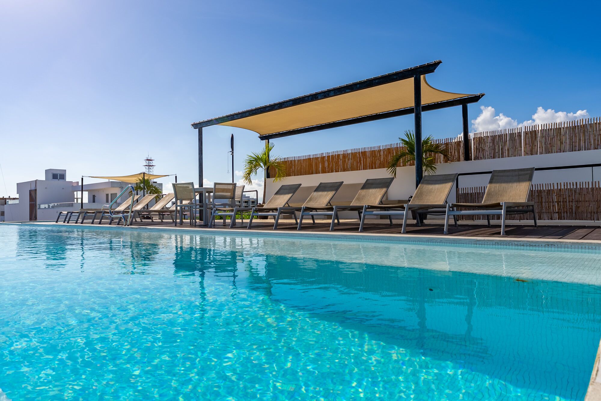 Une piscine dotée de chaises longues et d’un auvent.