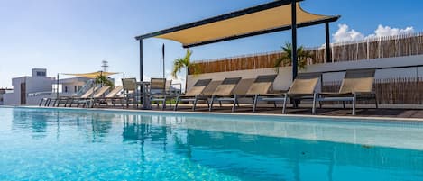A swimming pool with lounge chairs and a canopy.
