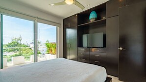 Ein modernes Schlafzimmer mit einem großen Bett, integriertem Kleiderschrank und einem Fernseher.