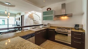 Eine moderne Küche mit Granitarbeitsplatten, einem eingebauten Backofen, einer Mikrowelle und einer Edelstahl-Dunstabzugshaube.